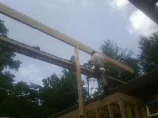 Carpenter setting a ridge beam over a new addition frame — Ice Dam Removal by Roofing Brothers in Wimberley
