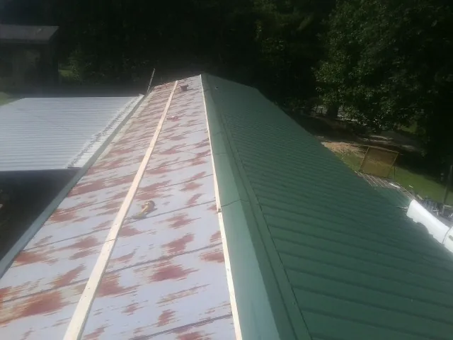 Old rusted panels beside newly installed green metal roofing — Wind Damage Roof Repair by Roofing Brothers in Wimberley