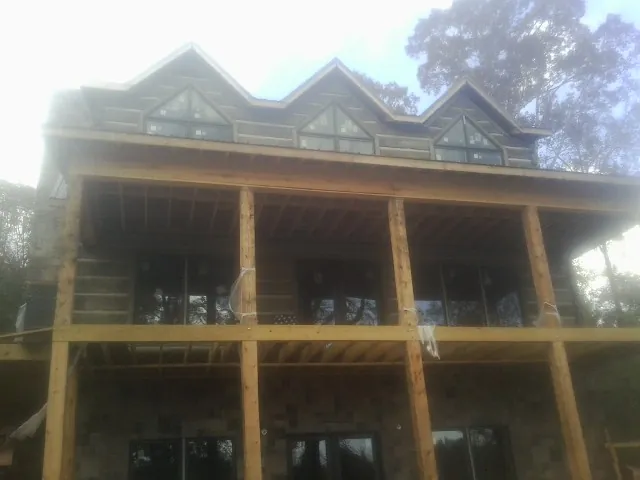 Dormers and porch framing on a large log home under construction — Roof Coating work by our crew in Wimberley