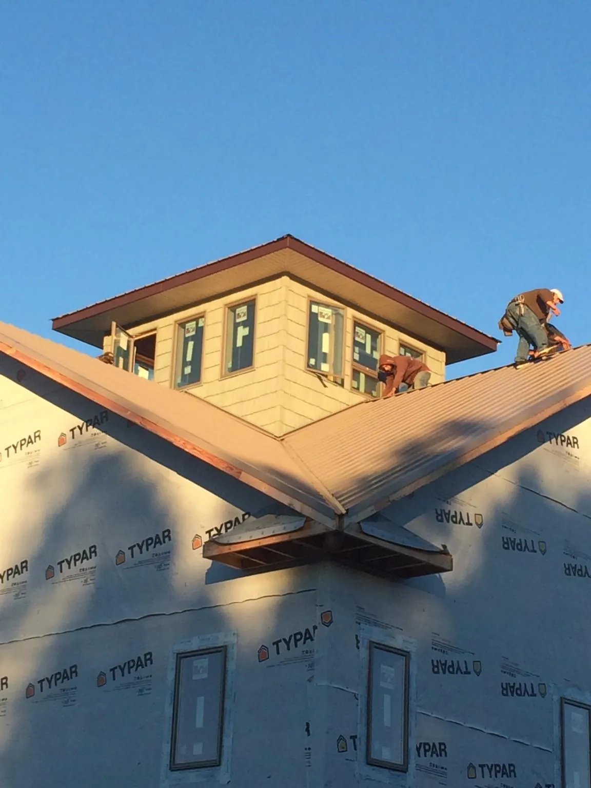 Roofers working around a rooftop cupola on a new metal roof at sunset — Roof Waterproofing in Wimberley by Roofing Brothers